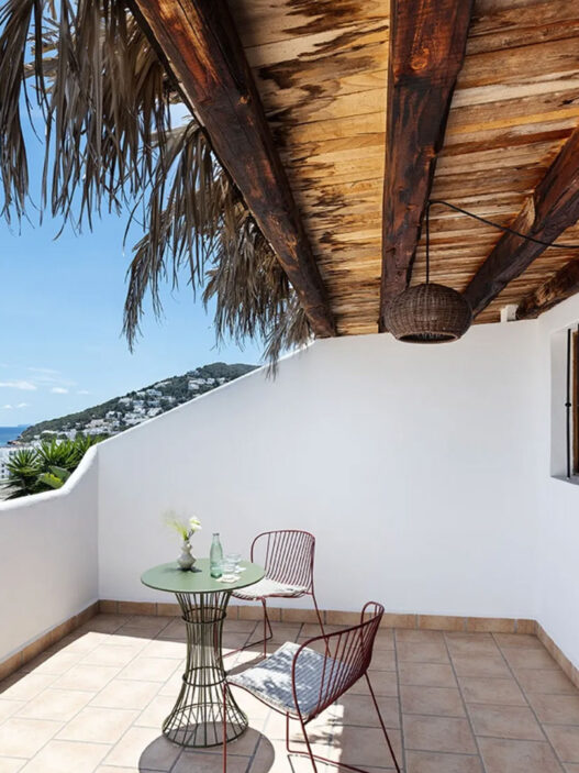 Terraza de One Shot Buenavista en Ibiza con techo de madera, paja y vistas al mar de Santa Eulalia