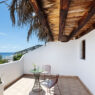 Terraza de One Shot Buenavista en Ibiza con techo de madera, paja y vistas al mar de Santa Eulalia
