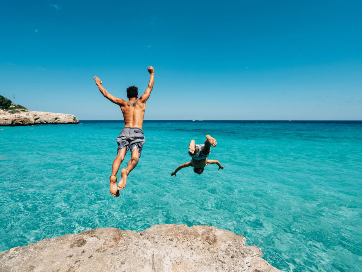 dos amigos saltando al mar desde unas rocas