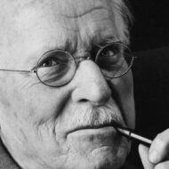 Carl Jung, psicólogo: "Todo lo que nos irrita de otros nos lleva a un entendimiento de nosotros mismos" Retrato en blanco y negro de Carl Gustav Jung con gafas redondas, sosteniendo su pipa y mirando a cámara.