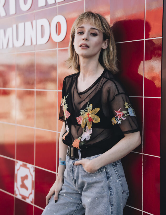 Maggie Civantos con top de tul negro de flores bordadas frente al mural del Hennessy Clúb en los conciertos de Bad Bunny en Madrid