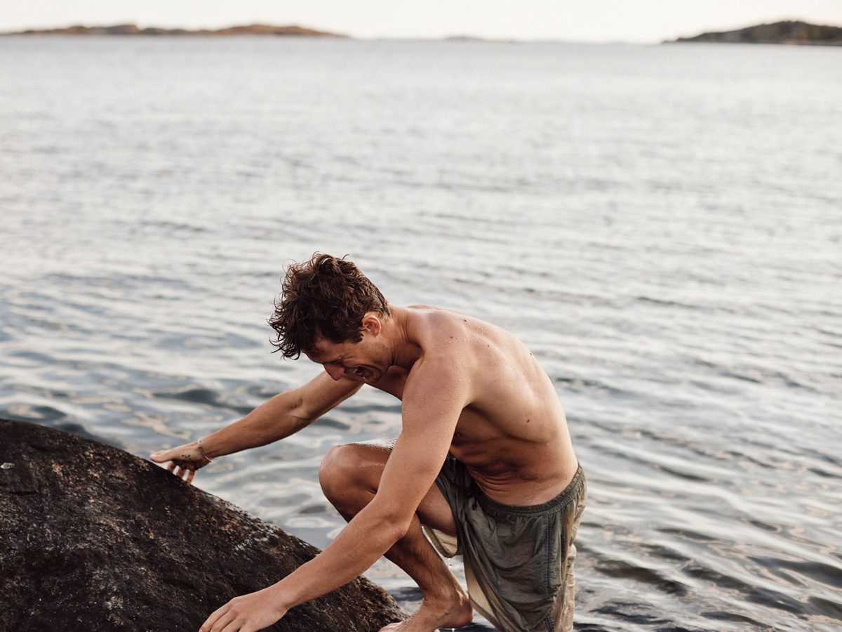 hombre bajando al mar desde rocas