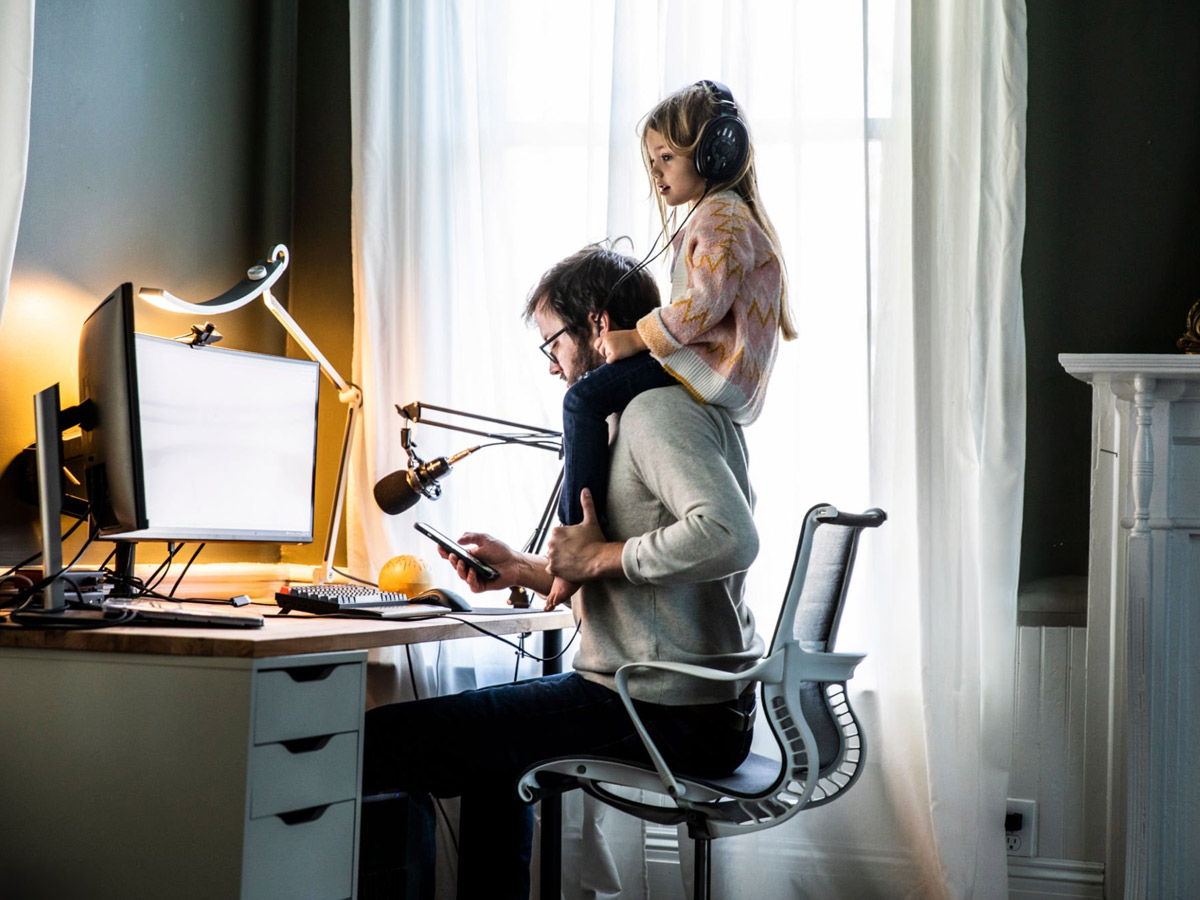 Hombre trabajando frente al ordenador y cuidando de su hija