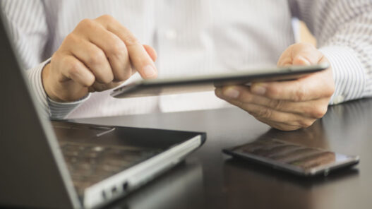 manos de un hombre trabajando con la tablet el ordenador y el móvil a la vez