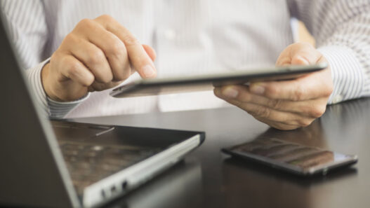 manos de un hombre trabajando con la tablet el ordenador y el móvil a la vez