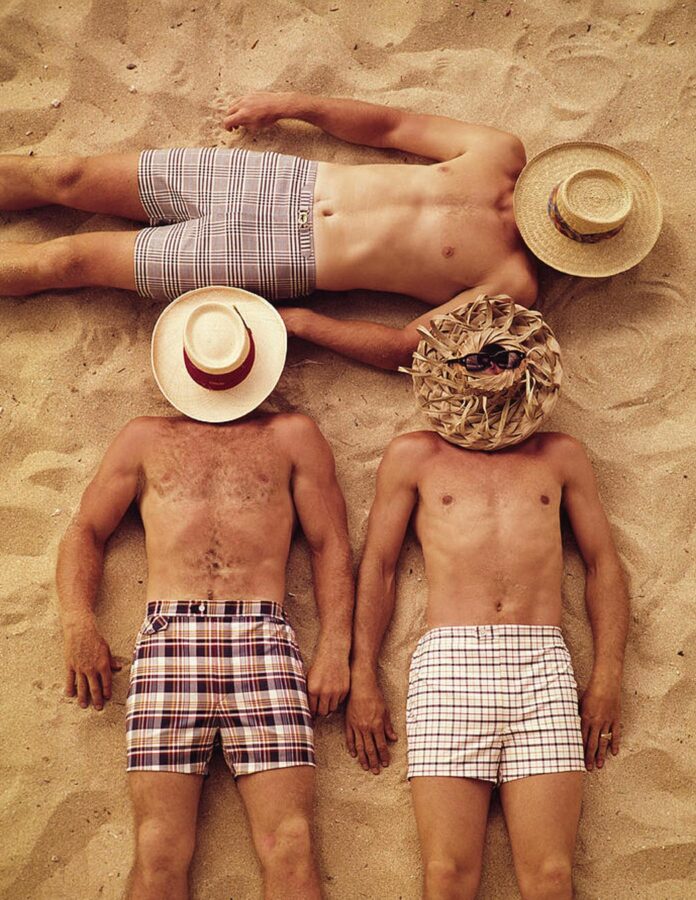 hombres tumbados en la arena de la playa con sombrero tapando la cara