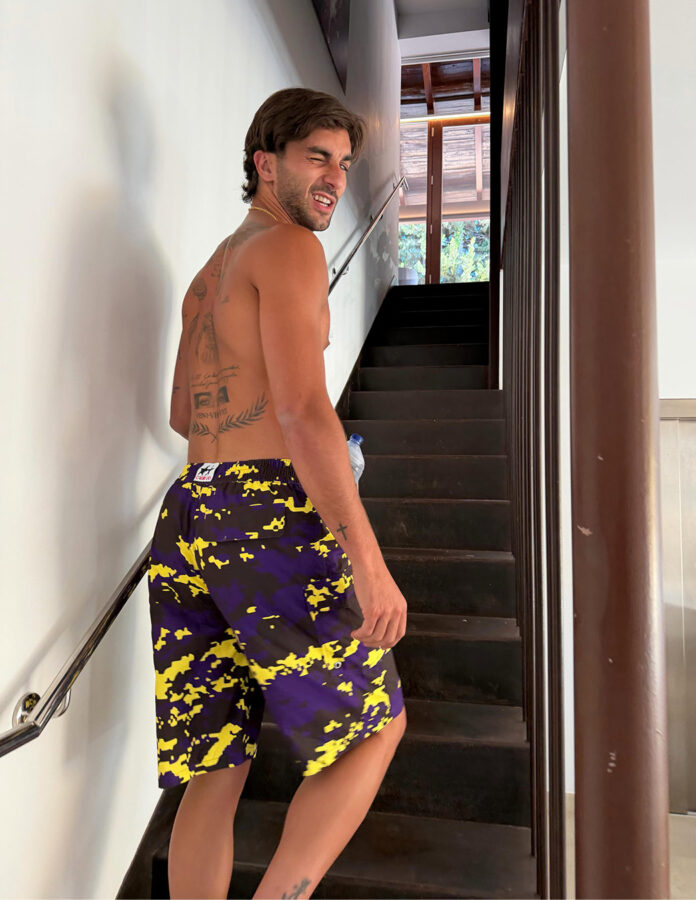 Ferran Torres subiendo unas escaleras con el bañador de camuflaje morado y amarillo de Twojeys