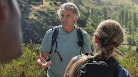 Jesús Calleja con camiseta y mochila de hidratación Quechua conversa con una participante en la montaña leonesa