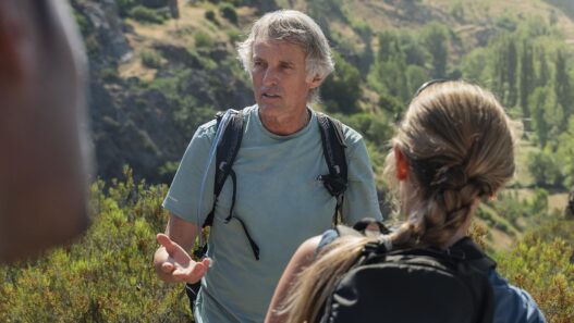 Jesús Calleja con camiseta y mochila de hidratación Quechua conversa con una participante en la montaña leonesa