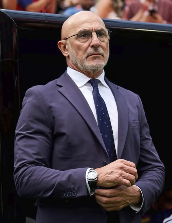 Luis de la Fuente en Luis de la Fuente con traje azul se ajusta el puño de la camisa y muestra su reloj IWC en la muñeca