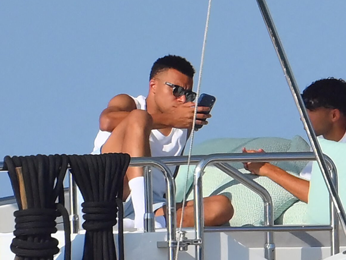 Kylian Mbappé consulta su móvil sentado en la cubierta de un yate Mangusta durante sus vacaciones en la Riviera Francesa