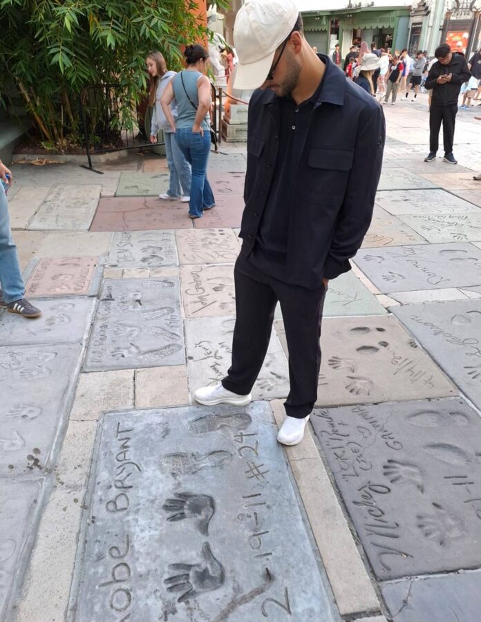 Mikel Merino con gorra blanca y look negro ante la placa de Kobe Bryant en Hollywood Boulevard