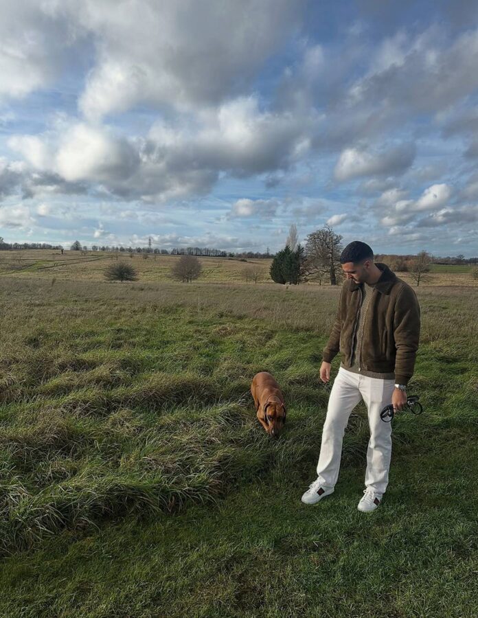 Mikel Merino pasea a su perro con chaqueta de ante, vaqueros blancos y zapatillas Gucci Ace