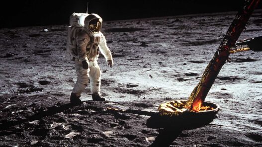 Astronauta del Apolo 11 caminando sobre la superficie lunar junto a la pata dorada del módulo lunar Eagle.