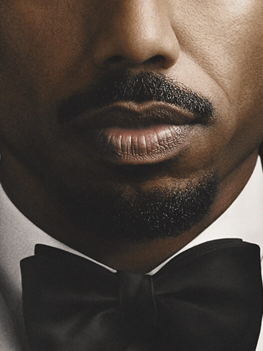 Michael B. Jordan con esmoquin blanco y pajarita negra en la imagen promocional de El Secreto de Thomas Crown