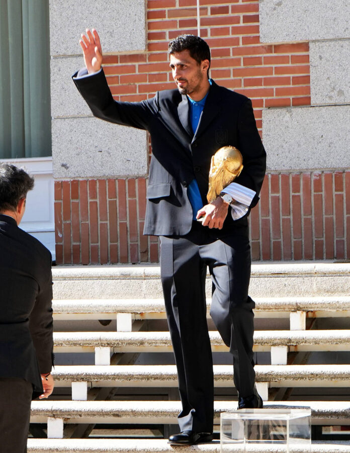 Rodri Hernández saluda a su llegada al Palacio de la Zarzuela con el trofeo del Mundial 2026 bajo el brazo y traje azul marino de Loewe