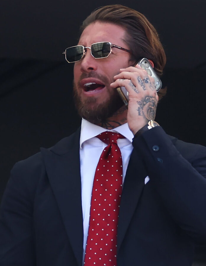 Sergio Ramos habla por teléfono en el palco de la final del Mundial 2026 con gafas de sol rectangulares y corbata roja de lunares