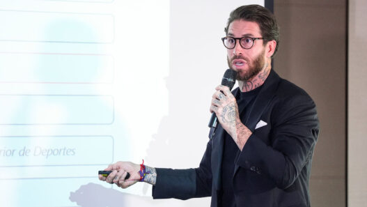 Sergio Ramos con gafas y un puntero frente a una pizarra explicando algo