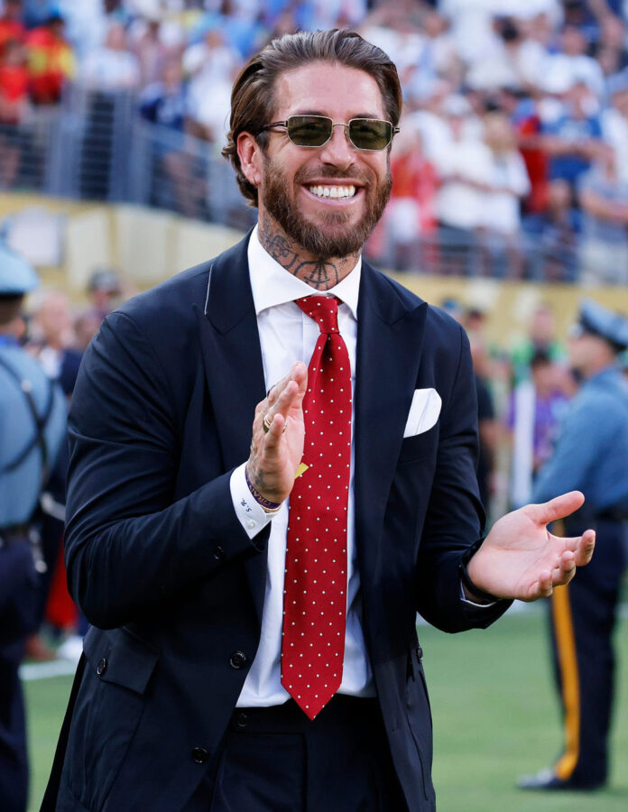 Sergio Ramos sonríe a pie de campo con traje azul marino, corbata roja de puntos blancos y gafas de sol Tom Ford tras la final del Mundial 2026