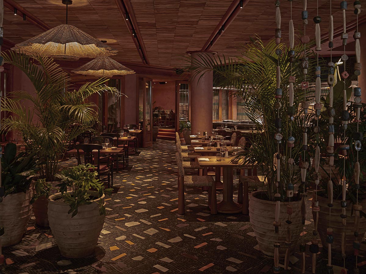 Comedor del restaurante Arroz y Fuego en el hotel Seaside Los Jameos de Lanzarote, con mesas de madera, plantas y lámparas de fibra natural