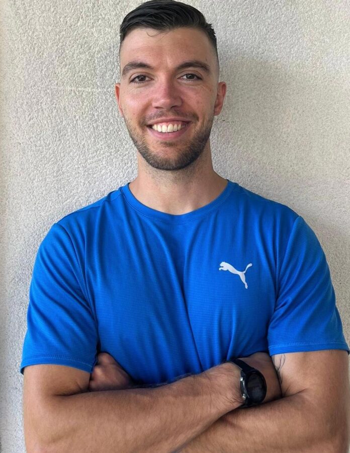 Alfonso García Quintero, entrenador personal, posando sonriente con camiseta deportiva azul