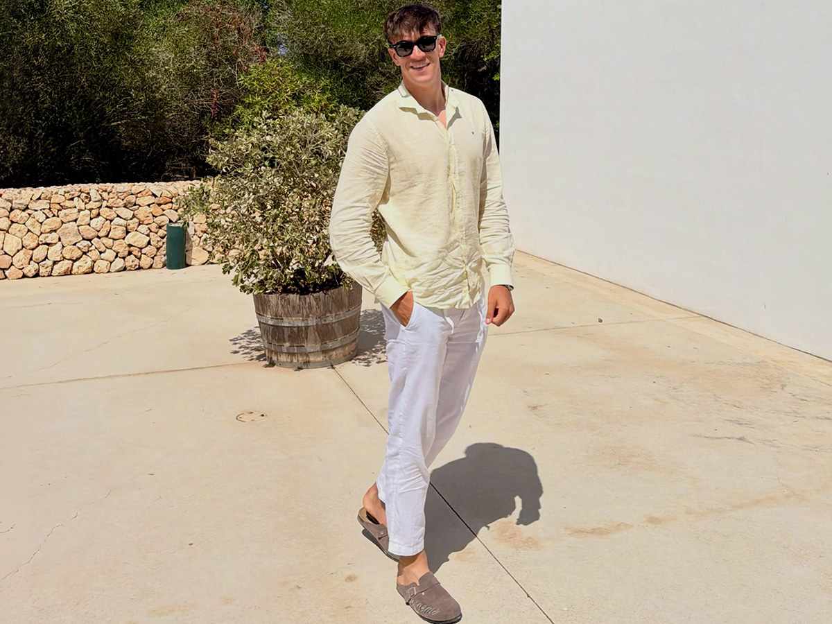 Carlos Espí, delantero del Real Madrid, con camisa de lino amarilla, pantalón blanco y zuecos de ante en un ambiente mediterráneo