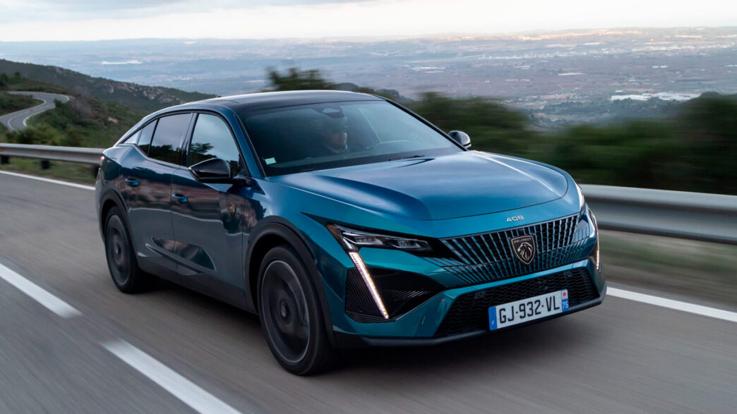 Peugeot 408 azul circulando por una carretera de montaña con valle al fondo