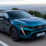 Peugeot 408 azul circulando por una carretera de montaña con valle al fondo