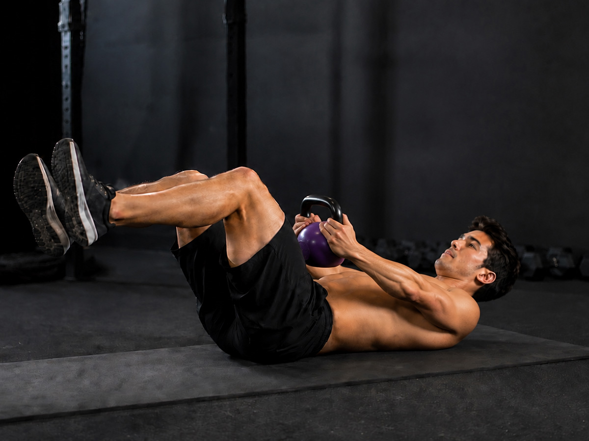 Último paso del dead bug: bajar la kettlebell hasta el abdomen manteniendo las piernas elevadas