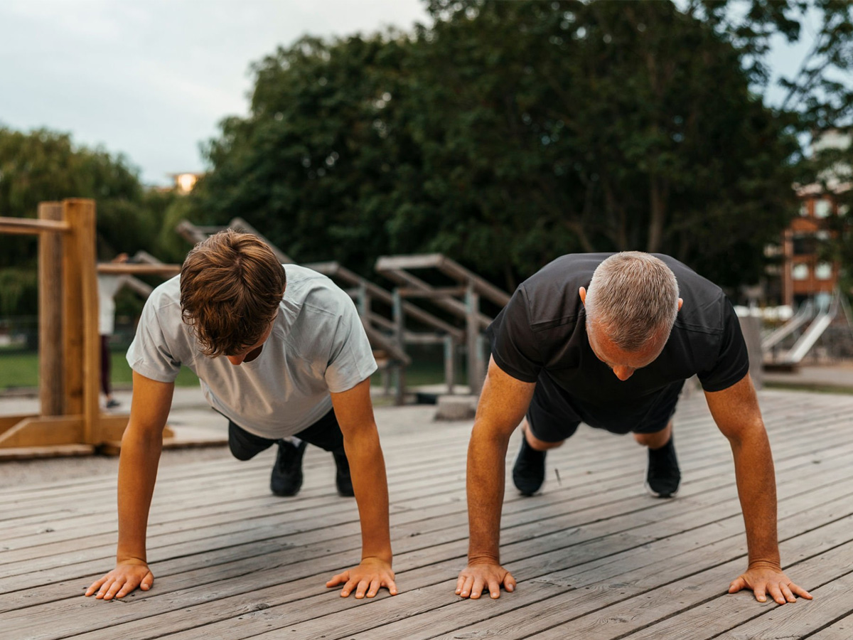 Dos hombres haciendo flexiones al aire libre para ganar fuerza en el tren superior sin gimnasio