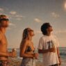 tres chicos contemplando el eclipse con gafas de sol y una cervza en la mano
