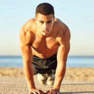 Ni gimnasio ni mancuernas: el ejercicio recomendado para aumentar el pectoral que puedes hacer en verano Hombre haciendo flexiones en la playa para entrenar el pectoral en verano sin material