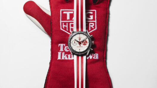Edición limitada TAG Heuer Carrera Chronograph x Team Ikuzawa sobre un guante de competición rojo con los logotipos de la escudería japonesa
