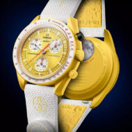 El eclipse solar ya tiene reloj: cuesta 280 euros, reproduce el instante en que el Sol desaparece y solo se vende hoy Reloj amarillo Swatch MISSION TO THE SUN - SOLAR ECLIPSE exhibido por delante y por detrás sobre fondo oscuro