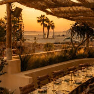 Terraza del restaurante Madunia en Ibiza al atardecer, con mesas bajo pérgola de madera y vistas al mar