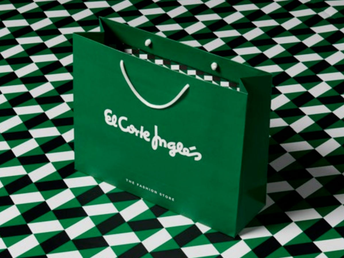 Bolsa verde de El Corte Inglés con logotipo y asas blancas sobre un fondo de estampado geométrico.