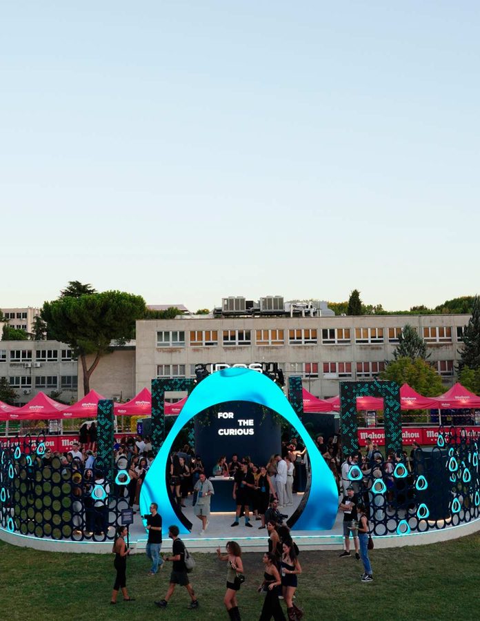 Vista aérea de la House of IQOS en Zamna Madrid con el arco azul «For the Curious» y asistentes en el recinto de día