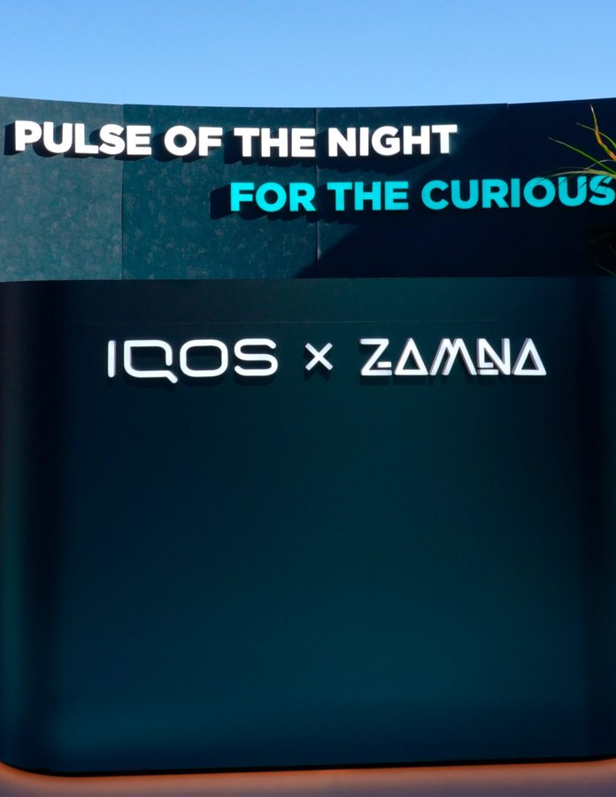 Rótulo «Pulse of the Night. For the Curious» con el logo IQOS x Zamna en la fachada del stand