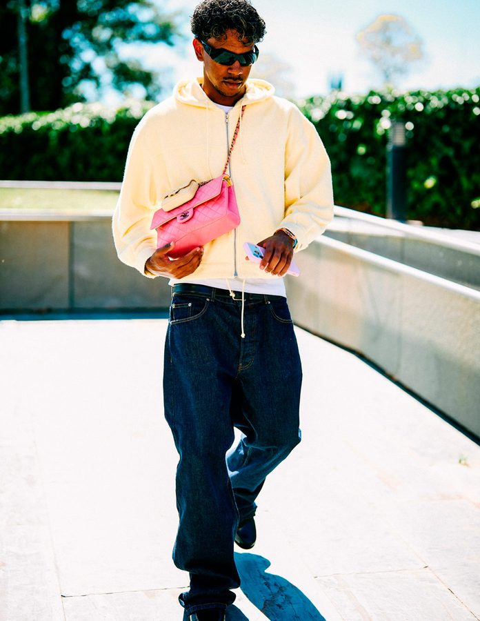 Lamine Yamal caminando con sudadera con capucha color crema, vaqueros oscuros, gafas de sol negras y bolso rosa de Chanel en Las Rozas