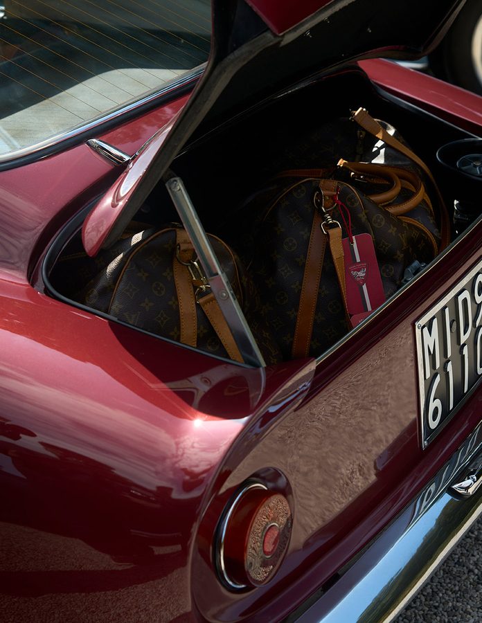 Maletero de un coche clásico rojo con bolsas Louis Vuitton de lona Monogram durante la Dolomites Classic Run 2026
