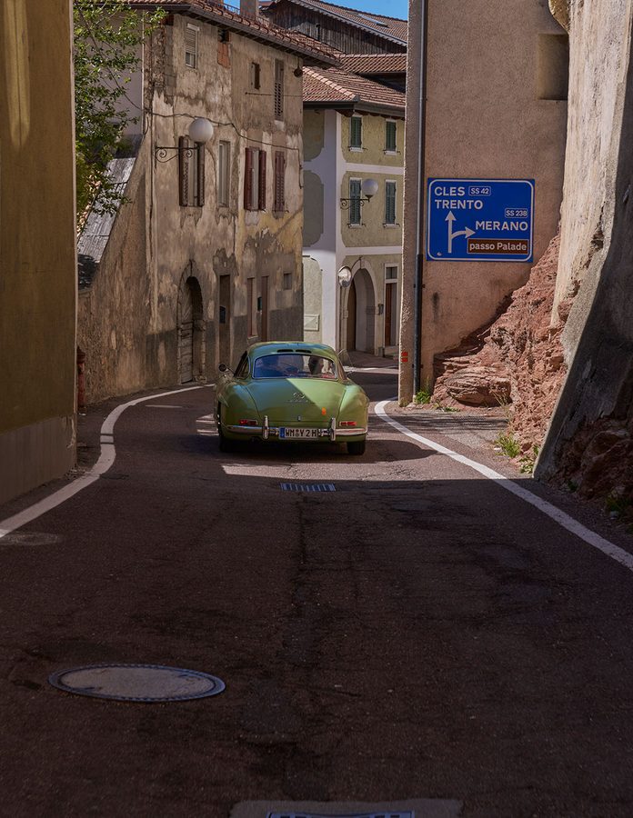 Mercedes 300 SL verde atravesando un pueblo de montaña camino del Passo Palade en la Louis Vuitton Dolomites Classic Run 2026