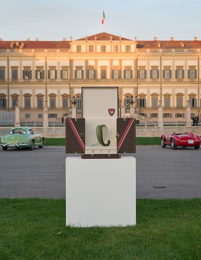 Trophy Trunk de Louis Vuitton abierto con el trofeo de cristal de Venini frente a Villa Reale di Monza