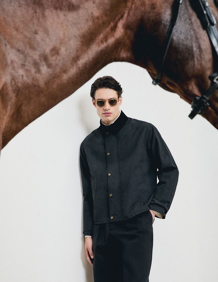 Modelo con gafas de sol Mó DOMA de montura clara y lentes verdes junto a un caballo