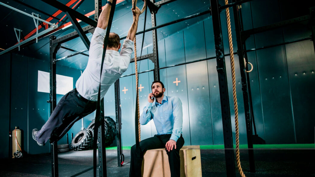 dos hombres vestidos de oficina entrenando en un gimnasio.