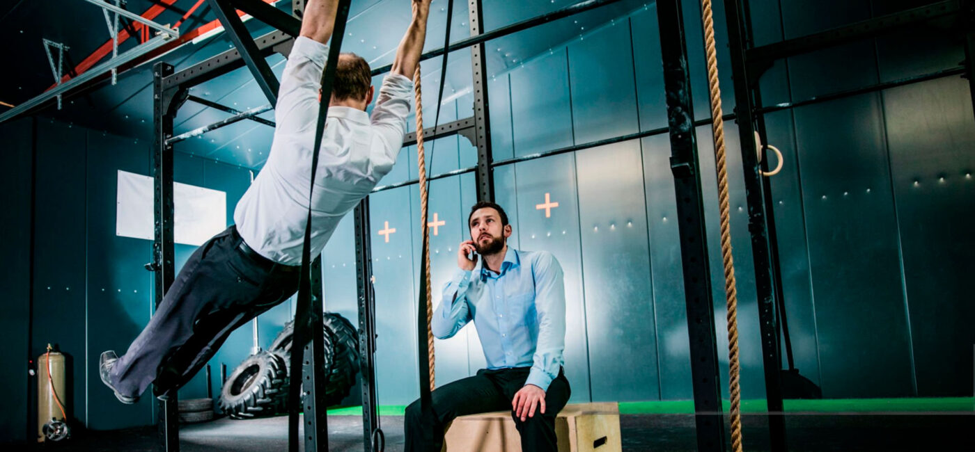 dos hombres vestidos de oficina entrenando en un gimnasio.