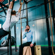 BuildMode, el nuevo gimnasio de Madrid para emprendedores donde tu entrenamiento depende de cómo va tu empresa dos hombres vestidos de oficina entrenando en un gimnasio.