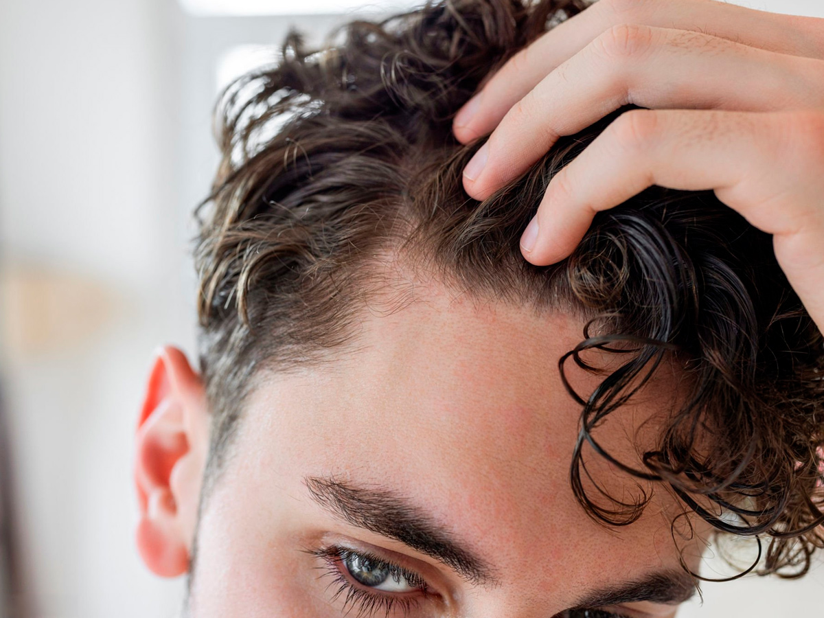 hombre joven mirándose la entrada del cabello