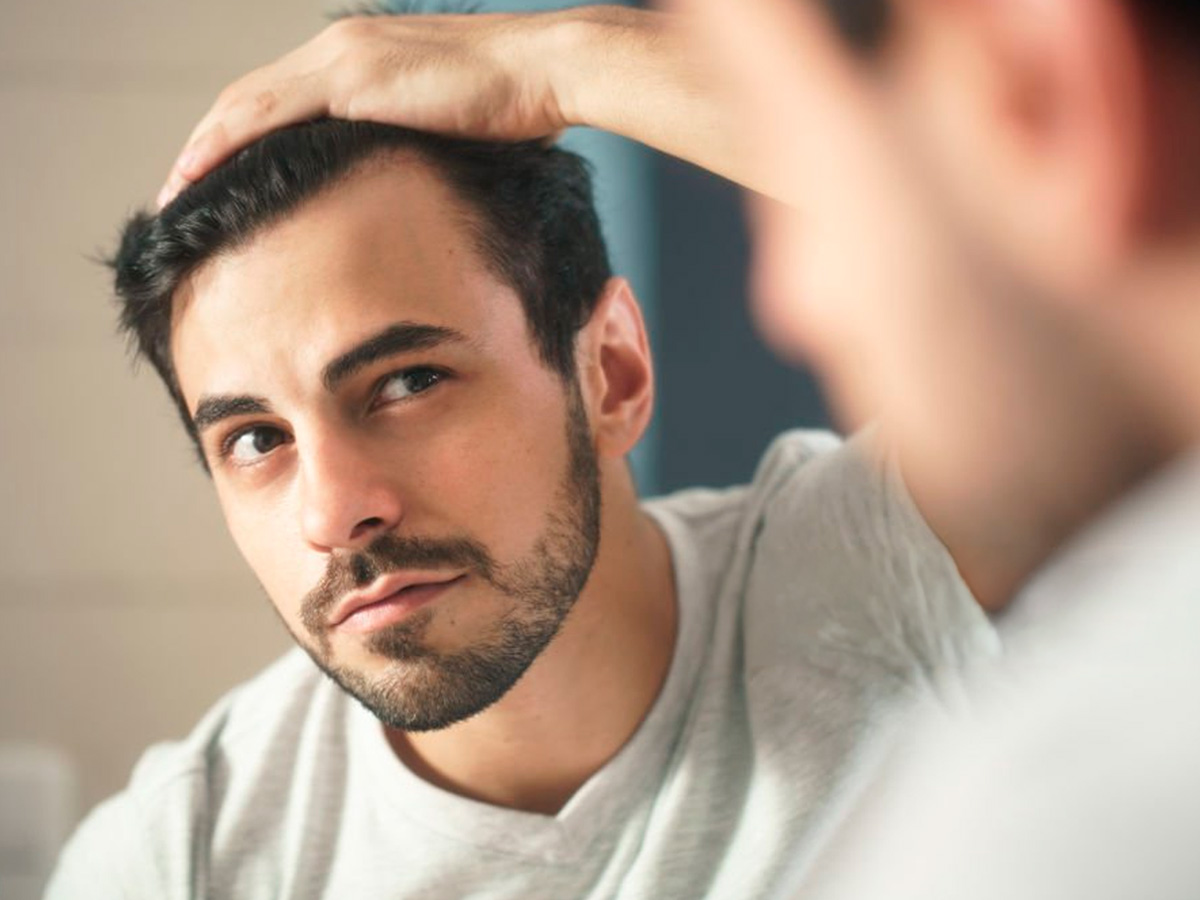 hombre mirándose pelo en espejo