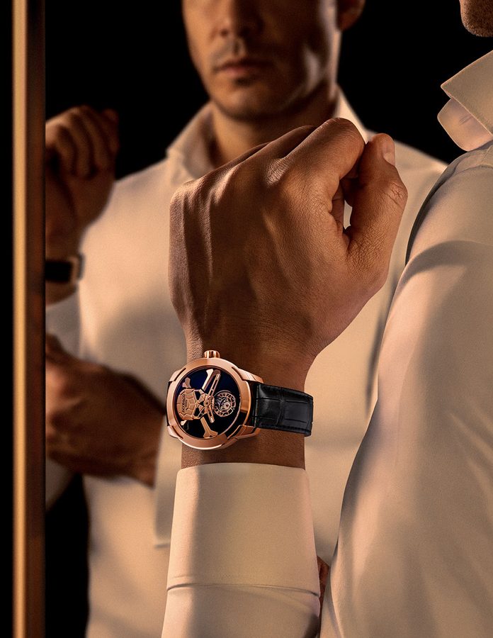 Hombre con camisa blanca frente a un espejo luciendo el Jacob & Co. Skull Tourbillon en oro rosa con correa de piel negra