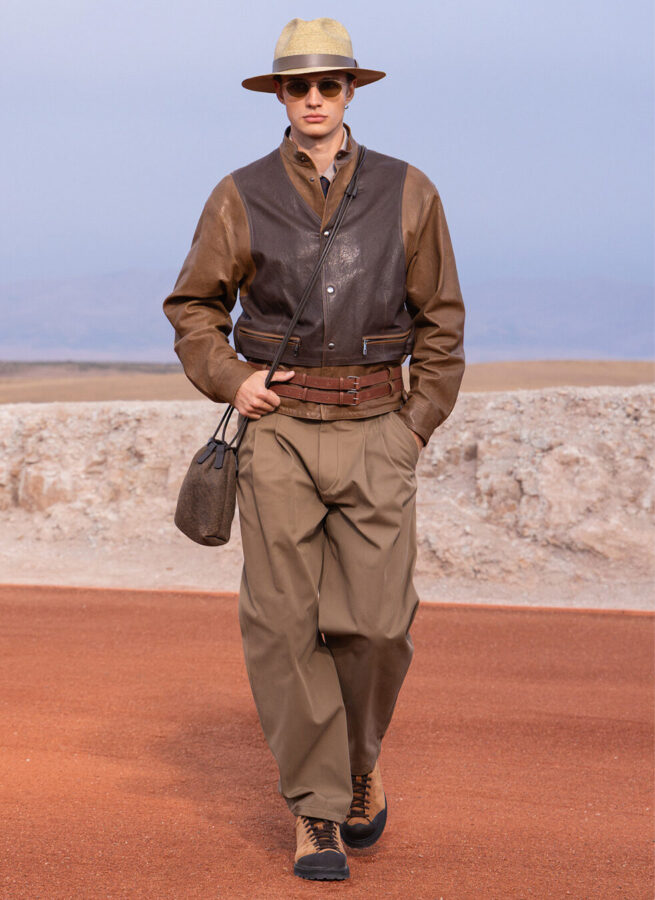 Modelo con chaqueta de cuero bicolor marrón, cinturón doble, pantalón ancho y sombrero de paja de Giorgio Armani & Kith